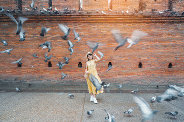 Wall Mural - Young asian woman traveler in Yellow dress with hat and bag traveling on Tha Pae Gate, Tourist visit at the old city in Chang Mai, Thailand. Asia Travel, Vacation and summer holiday concept