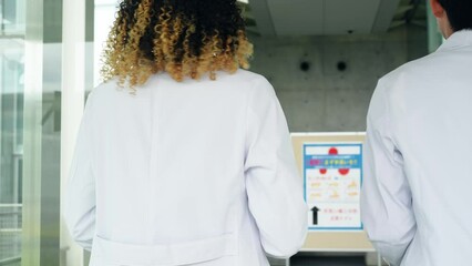 Poster - 白衣を着て施設を歩く多国籍グループ