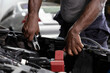 © offsuperphoto - close up mechanic worker hands holding battery cable for jumping battery of a car in automobile repair shop