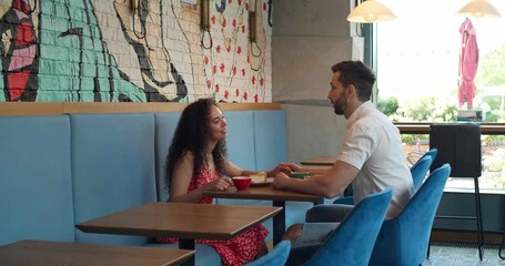 Poster - Happy couple spending time together in cafeteria. Camera moving towards them