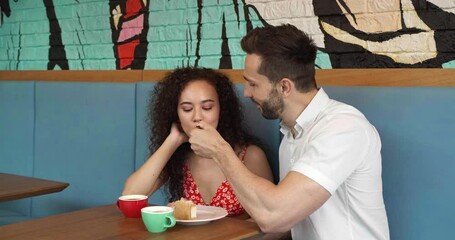 Poster - Happy couple spending time together in cafeteria. Man feeding his girlfriend with tasty cheesecake