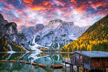 Wall Mural - Picturesque landscape with famous lake Braies in autumn Dolomites mountains during incredible sunset. Wooden boats and pier in clear water of Lago di Braies, Dolomite Alps, Italy