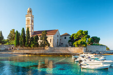 Turquoise Water Of Adriatic Sea Bay On Hvar Island With Franciscian Monastery And Boats In Dalmatia Region, Croatia At Sunrise