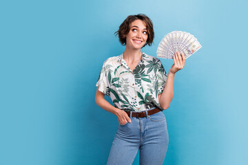 Photo of dreamy funny lady wear print shirt holding money fan looking empty space isolated blue color background