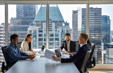 Happy busy international professional business team people working together at group meeting. Multiethnic diverse executive colleagues discussing financial project in office corporate board room.