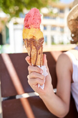 Crop child with delicious ice cream in cone on street