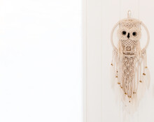 A Beautiful Hand Made Bohemian Dreamcatcher With A Crochet Owl And White Feathers Hanging On A White Door With Light Coming From The Window On The Left.