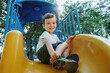 © alexkoral - happy preschooler boy playing on slide on playground in summer