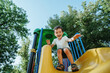 © alexkoral - happy preschooler boy playing on slide on playground in summer