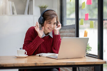 Wall Mural - Asian female student study online in class, study online, wearing headphones, watching video call, zooming, happy asian female learning language online with computer laptop.