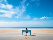 A Person Sitting On A Wooden Bench On The Beach