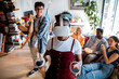 © Marko Geber - Young and diverse group of friends using a vr headset to play games together in the living room of their flatshare apartment