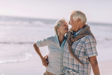 Senior Caucasian Couple Walking On A Sandy Beach On Their Vacation