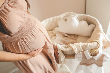 Wall Mural - Pregnant woman waiting for a baby in the nursery near the cradle