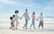 © Mumtaaz D/peopleimages.com - Summer, beach and a family holding hands while walking on the sand by the ocean or sea together. Grandparents, parents and children outdoor in nature for travel, vacation or holiday on the coast