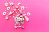Fototapeta Mapy - Shopping cart with flowers over fuchsia background. Holidays shopping and sale concept