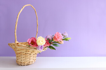 Wall Mural - image of delicate pink flowers in the wicker basket over wooden table and purple background