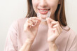 © KMPZZZ - Dental invisible braces, beautiful smiling asian young woman holding invisalign braces, wearing orthodontic silicone trainer, white smile using invisible whitening tray. Stomatology, dental healthcare