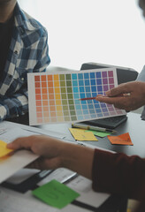 Close up ux developer and ui designer brainstorming about mobile app interface wireframe design on table with customer breif and color code at modern office.Creative digital development agency