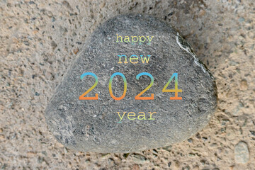 closeup the orange ,yellow ,sky, color with happy new year 2024 writing on the brown stone soft focus natural grey brown background.