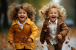 funny laughing children 4-5 years, two brothers or sisters, playing with autumn leaves in the park or in the forest