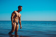 Portrait of a muscle handsome young man in balck swimwear posing in the sea