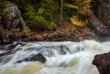 Wall Mural - Fast flowing water near a waterfall on a mountain river in autumn