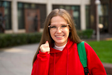 Wall Mural - beautiful young college or university student, happy girl outdoors at campus in glasses with braces. Portrait of teen, female teenager in red hood