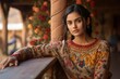 A beautiful Indian princess wearing a double-knitted sweater with a floral design poses candidly in front of a traditional Rajasthani fort. generative ai