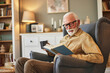 © Stockphotodirectors - Elderly man sitting in armchair and reading a book at home