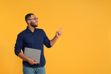 Poster - Smiling young man with laptop on yellow background, space for text