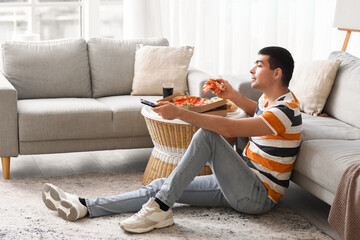 Sticker - Young man with tasty pizza watching TV at home