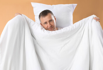 Poster - Mature man with soft pillow and blanket on beige background