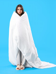 Sticker - Sleepy young woman with soft blanket on blue background