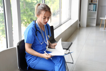 Sticker - Female medical intern writing in clipboard at hospital