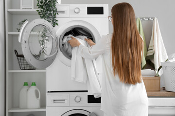 Wall Mural - Woman putting dirty clothes into washing machine in laundry room