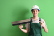 Male worker pointing at putty knife on green background