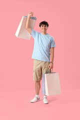 Canvas Print - Young man with shopping bags on pink background