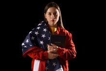 Young Woman With Bible And USA Flag On Dark Background