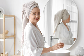 Wall Mural - Young woman with cream after shower near mirror in bathroom