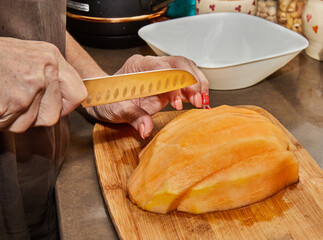 Wall Mural - Chef cuts melon into slices on wooden board in the kitchen