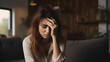 © AspctStyle - Depressed and unhappy woman sitting on sofa at home. Sad and tired young woman suffers from headache closed eyes touch forehead sitting on couch thinking over health problems, loneliness, bad news,