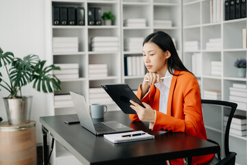  Beautiful Asian business woman typing laptop and tablet Placed at the table at the modern office..