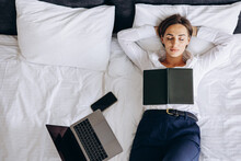 Business Woman Sleeping In A Hotel Room With Laptop And Phone Lying On Bed