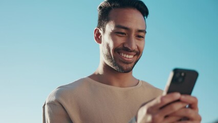 Poster - Blue sky, phone and young man typing a text message on social media, mobile app or website. Technology, online and happy Indian male person scroll on the internet with a cellphone for communication.