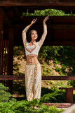 Fototapeta Nowy Jork - joyful and graceful indian woman in authentic style attire dancing and looking away in summer park