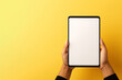 © degungpranasiwi - Hand holding tablet with mockup blank screen isolated on yellow background with copy space
