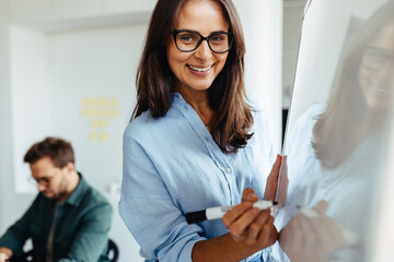 Poster - Happy business woman writing her ideas on a board during a meeting