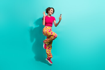 Poster - Full length photo of adorable friendly lady flower print pants jumping recording video vlog gadget isolated turquoise color background