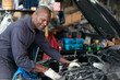 © offsuperphoto - African mechanic worker checking and fixing a car in garage